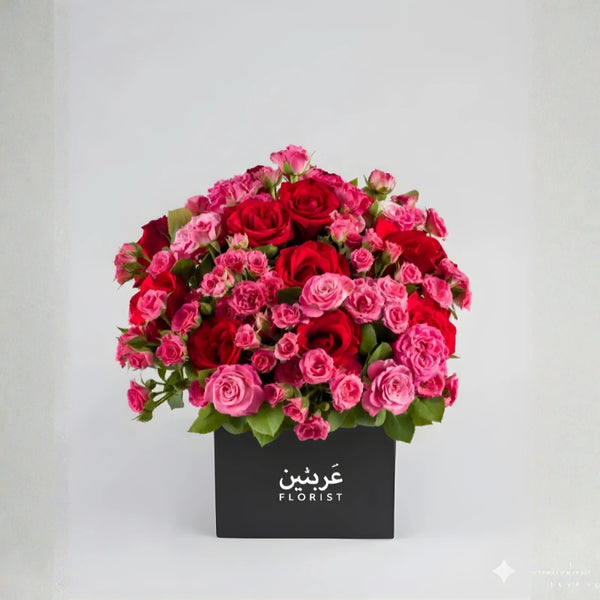 Bouquet of red and pink roses in a black box with 'Arabesque Florist' branding on a light gray background.