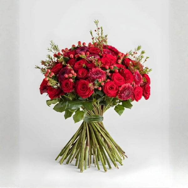 Bouquet of red and pink flowers with greenery on a white background