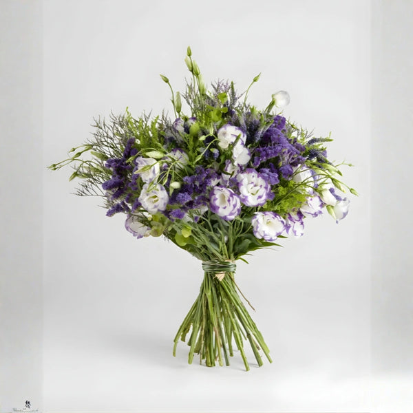 Bouquet of purple and white flowers in a clear vase on a light gray background